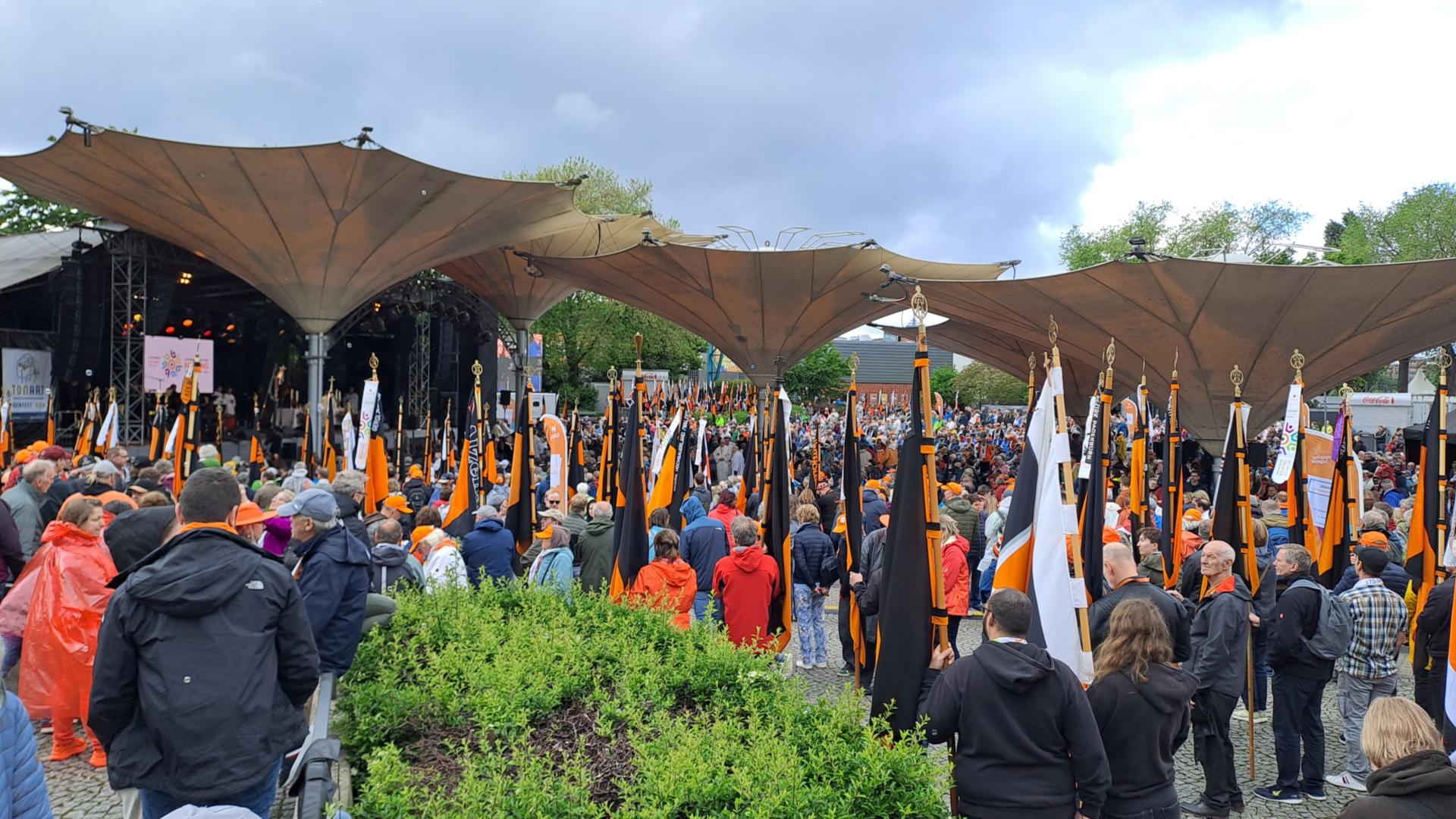 Viele Menschen stehen mit Kolping-Fahnen vor einer Open Air Bühne